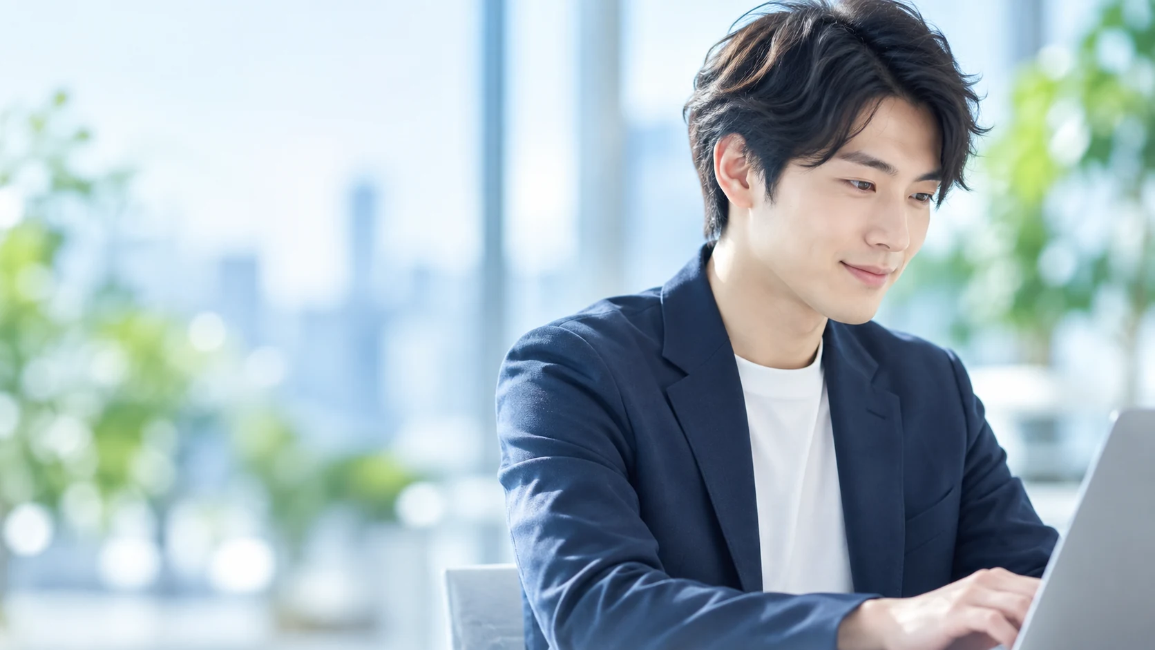 明るいオフィスで、ノートパソコンに向かって仕事をする社員