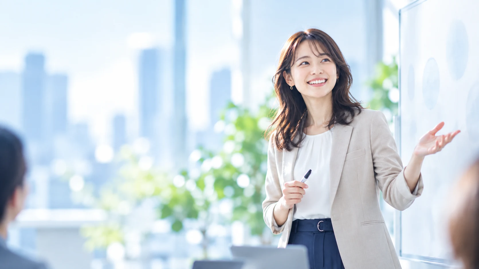ホワイトボードの前で、笑顔でプレゼンテーションをする社員